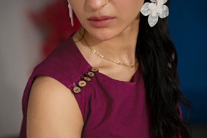 Close-up of shoulder buttons and cross-panel design on dark purple sleeveless top